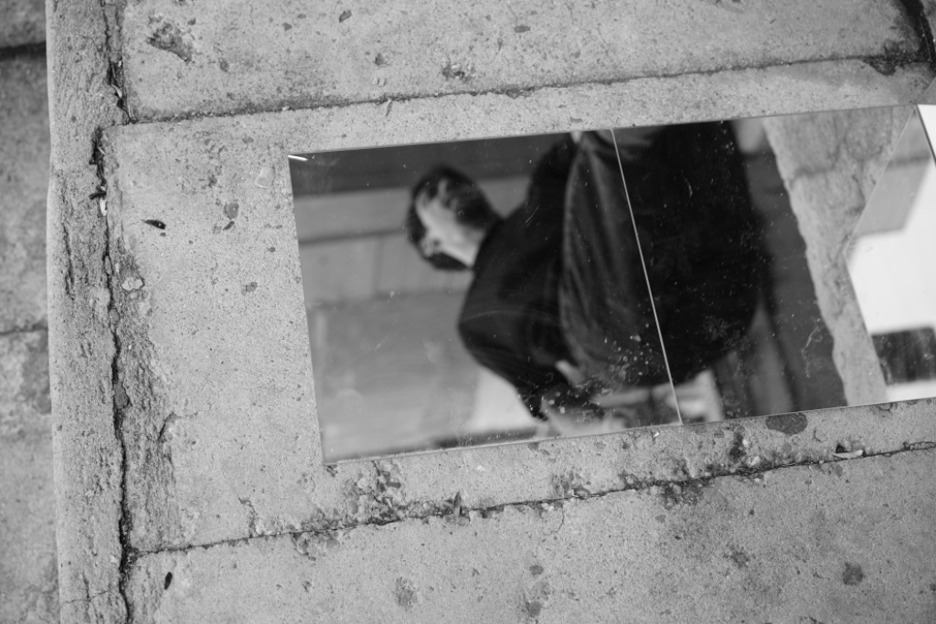 Roman reflected in a mirror placed on cracked pavement