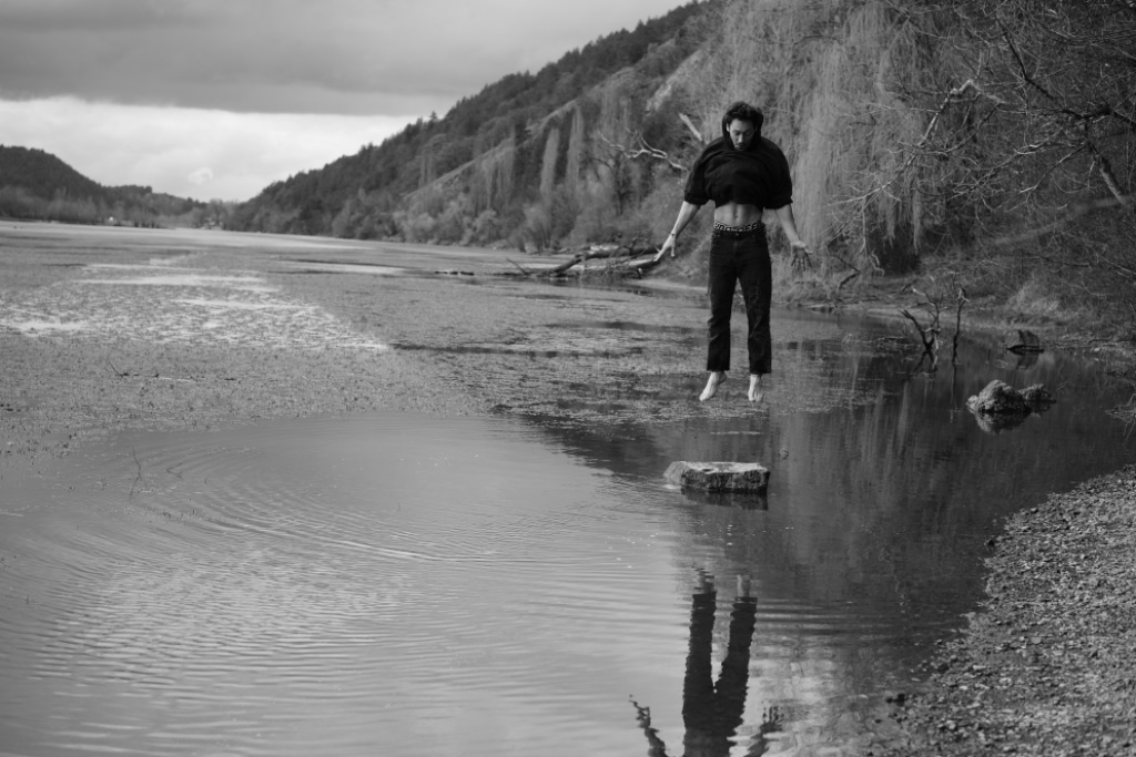 Roman hovering above a rock at a still lake, reflection below
