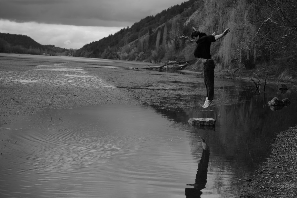 Roman leaping with arms wide over a still lake