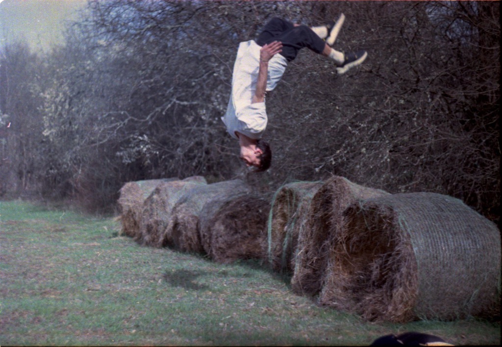 Roman mid-backflip above hay bales, dusk light